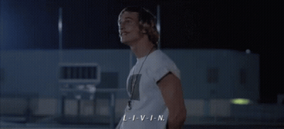 A Man In A White Shirt With A Necklace Around His Neck Says L-I-V-I-N GIF