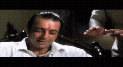 A Man In A White Shirt With A Red Spot On His Forehead Is Sitting On A Chair . GIF