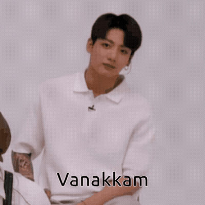 A Man In A White Shirt With His Hands Folded And The Word Vanakkam On The Bottom GIF