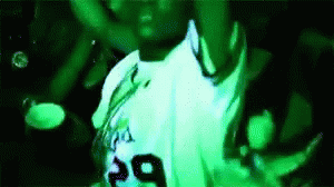 A Man In A White Shirt With The Number 29 On It Is Dancing In A Green Light . GIF