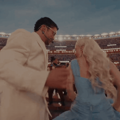 A Man In A White Suit And A Woman In A Blue Dress Are Dancing GIF