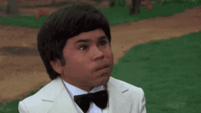 A Man In A White Suit And Bow Tie Is Making A Funny Face GIF