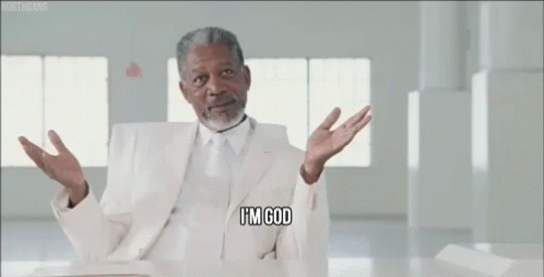 A Man In A White Suit And Tie Is Sitting At A Table And Saying I 'M God GIF