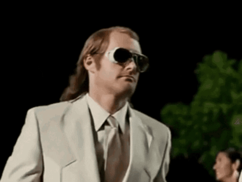 A Man In A White Suit And Tie Is Wearing Sunglasses . GIF