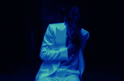 A Man In A White Suit Covering His Face With His Hand GIF