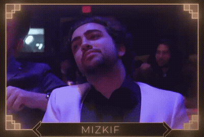 A Man In A White Suit Is Dancing In A Dark Room With The Name Mizkif On The Bottom Right GIF