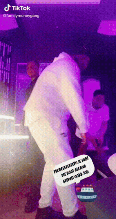 A Man In A White Suit Is Dancing In Front Of A Purple Background . GIF