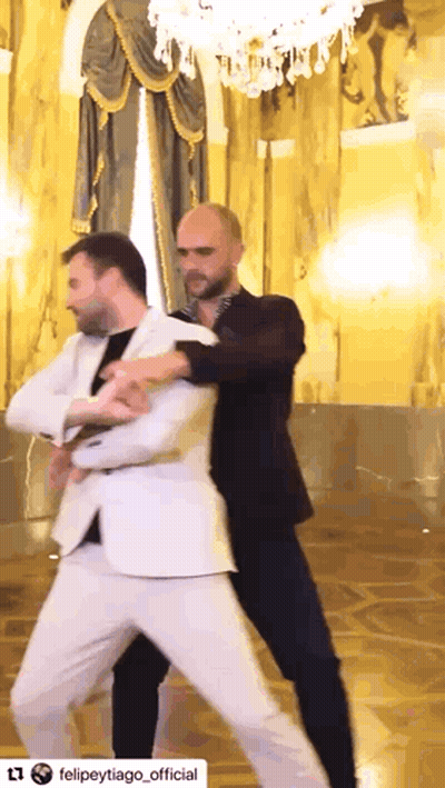 a man in a white suit is dancing with another man in black pants