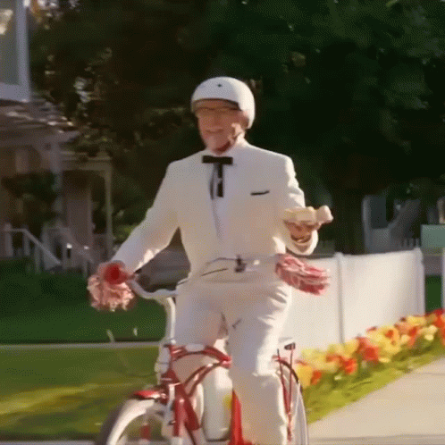 A Man In A White Suit Is Riding A Bike GIF