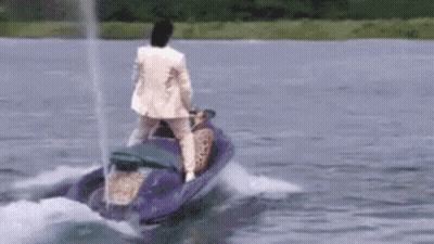 A Man In A White Suit Is Riding A Jet Ski On A Lake . GIF