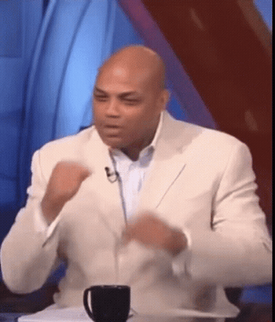 A Man In A White Suit Is Sitting At A Table With A Cup Of Coffee In Front Of Him GIF