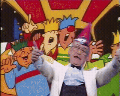 a man in a white suit is standing in front of a group of cartoon characters wearing party hats