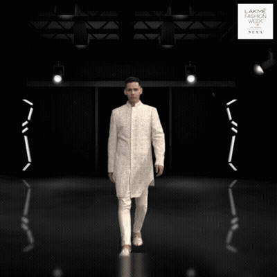 A Man In A White Suit Is Standing In Front Of A Lakme Fashion Week Sign GIF