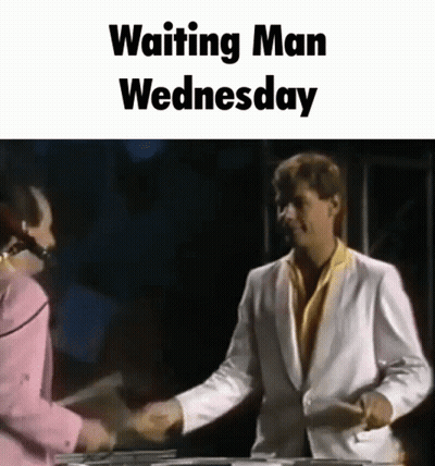 A Man In A White Suit Shakes Hands With A Woman In A Pink Shirt While Waiting For Wednesday . GIF