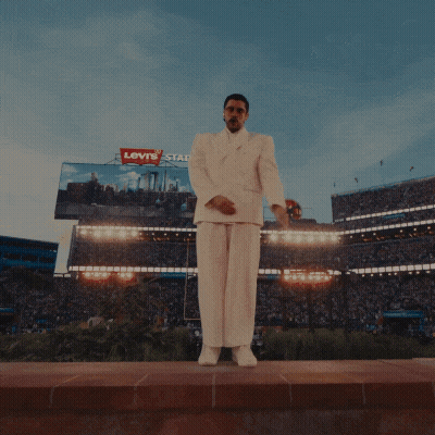 a man in a white suit stands in a crowd of people