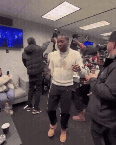 A Man In A White Sweater Is Dancing In A Room With People GIF