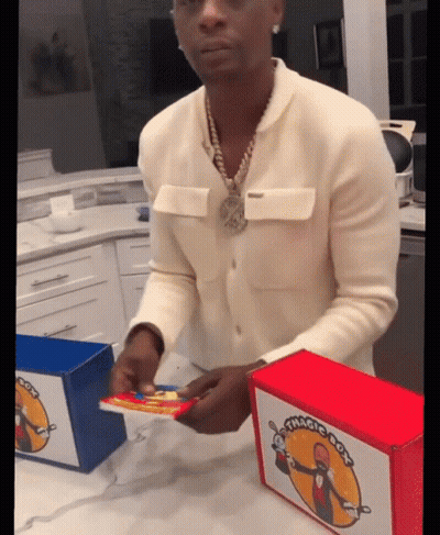 A Man In A White Sweater Is Opening A Box That Has The Word Magic On It GIF