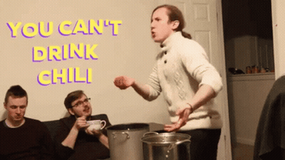 A Man In A White Sweater Is Standing In Front Of A Wall With The Words " You Can 'T Drink Chili " On It GIF