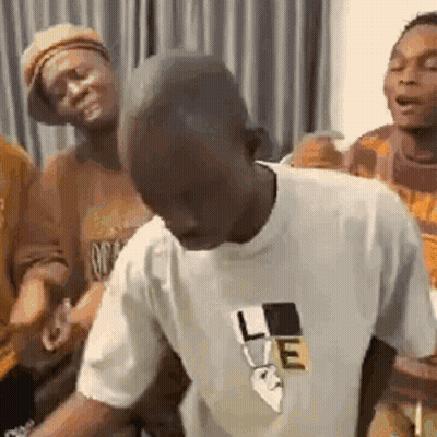 A Man In A White T-Shirt Is Dancing In A Room With Other People . GIF