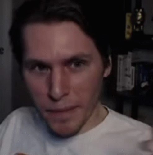 A Man In A White T-Shirt Is Making A Funny Face In Front Of A Camera . GIF