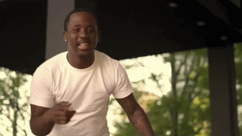 A Man In A White T-Shirt Is Smiling And Running GIF