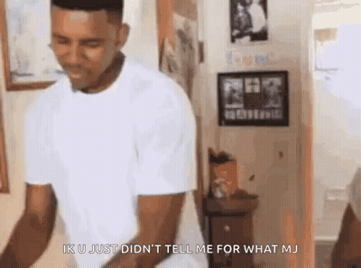 A Man In A White T-Shirt Is Standing In A Room . GIF