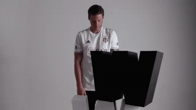 A Man In A White T-Shirt Is Standing Next To A Black Letter W . GIF