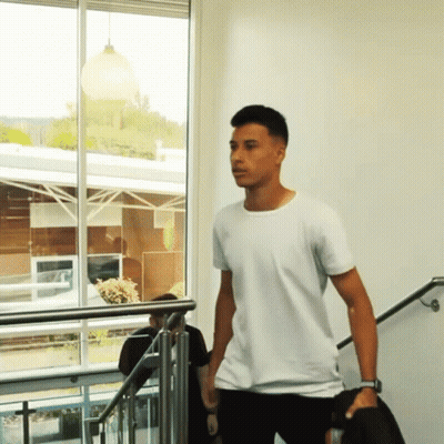 A Man In A White T-Shirt Is Walking Down Stairs GIF