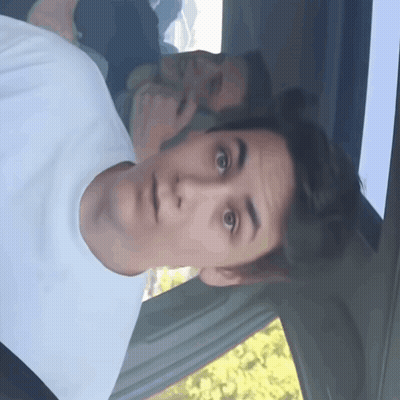 A Man In A White T-Shirt Looks Surprised In A Car GIF