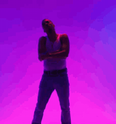 A Man In A White Tank Top And Blue Jeans Is Standing With His Arms Crossed In Front Of A Purple Background GIF