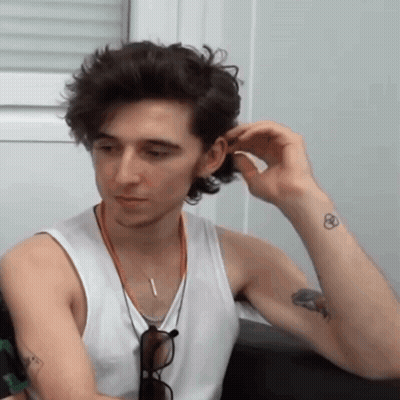 A Man In A White Tank Top Has A Tattoo On His Wrist GIF