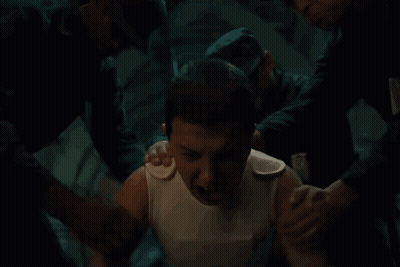 A Man In A White Tank Top Is Being Helped By Two Men . GIF