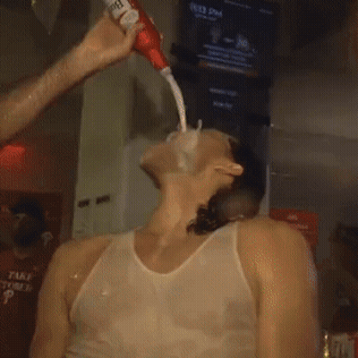 A Man In A White Tank Top Is Being Squirted With A Tube Of Toothpaste GIF