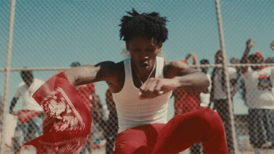 A Man In A White Tank Top Is Dancing In Front Of A Crowd GIF