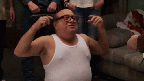 A Man In A White Tank Top Is Flexing His Muscles GIF