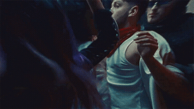 A Man In A White Tank Top Is Holding A Woman In A Crowd Of People GIF