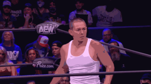 A Man In A White Tank Top Is In A Wrestling Ring With A Sign That Says Aek On It GIF