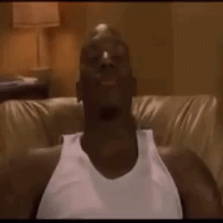 A Man In A White Tank Top Is Sitting On A Couch With His Head In The Air . GIF