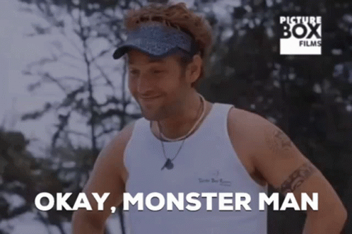A Man In A White Tank Top Is Smiling And Says " Okay Monster Man " GIF
