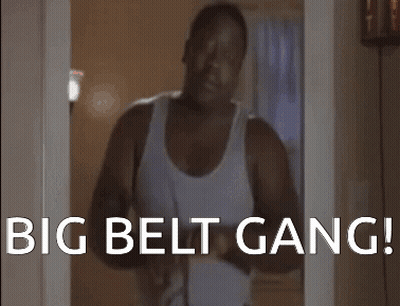 A Man In A White Tank Top Is Standing In A Doorway With The Words " Big Belt Gang " On The Bottom GIF