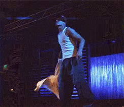 A Man In A White Tank Top Is Standing On A Stage GIF