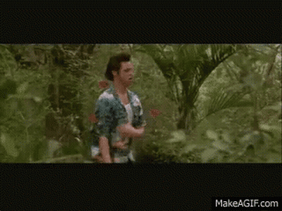 A Man In A White Tank Top Is Walking Through A Lush Green Forest GIF