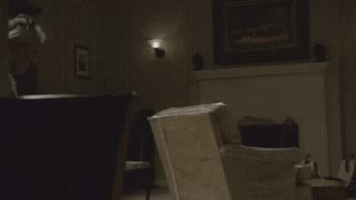 A Man In A White Tank Top Looks At Something GIF