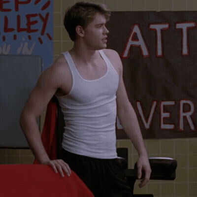 A Man In A White Tank Top Stands In Front Of A Sign That Says Att GIF