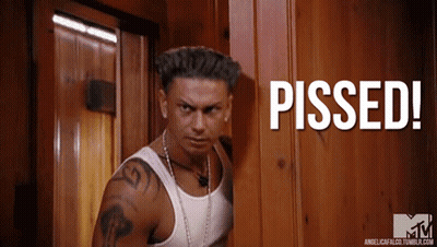 A Man In A White Tank Top Stands In Front Of A Wooden Door With The Words Pissed Written On It GIF