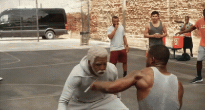 A Man In A White Tank Top With The Letter L On It Is Fighting Another Man On A Basketball Court GIF