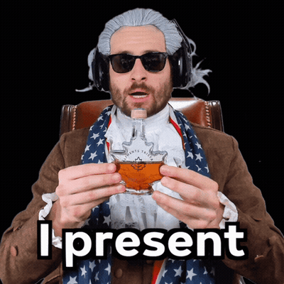 A Man In A Wig And Sunglasses Is Holding A Glass Of Maple Syrup And The Words I Present Behind Him GIF