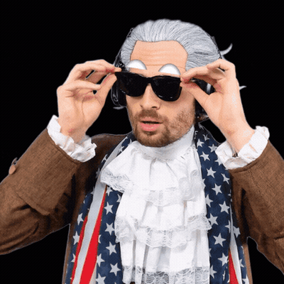 A Man In A Wig And Sunglasses Is Wearing An American Flag GIF