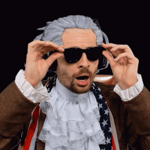 A Man In A Wig And Sunglasses Is Wearing An American Flag Scarf GIF
