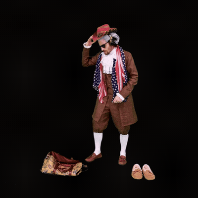 A Man In A Wig Is Holding An American Flag And A Backpack GIF